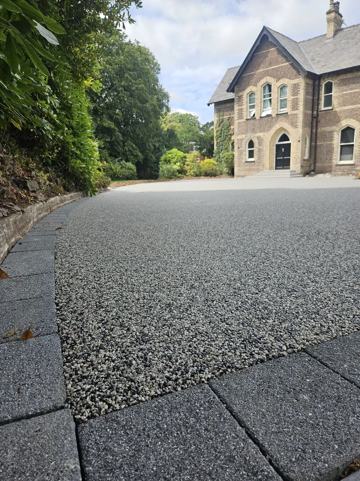 Moonshadow resin bound surfacing laid to a crisp granite sett border on a large scheme